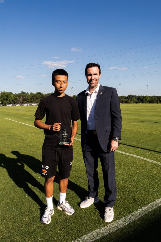 Houston Summers, Partner at Sasser Restoration, presenting the Restoring Tomorrow award to a Carolina Core Academy player.